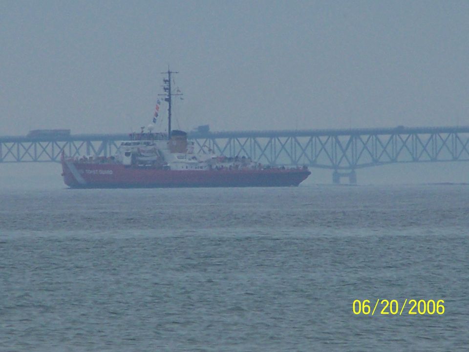 US Coast Guard cutter sailing on water with a bridge in the background