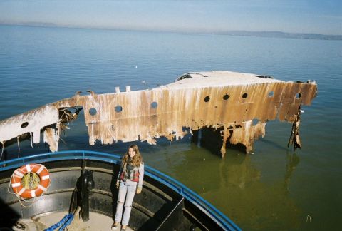 1991 Ford Bronco - A person stands on a boat deck overlooking a large, rusted shipwreck in the water.