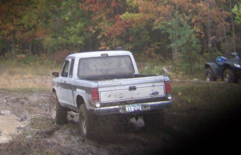 1978 Ford Bronco - A silver 1978 Ford F-150 pickup truck navigates a muddy terrain with an ATV visible in the background.