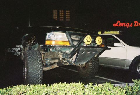 1991 Ford Bronco - A modified truck with off-road tires and a custom bumper is parked at night. A sign for Longs Drugs is visible.