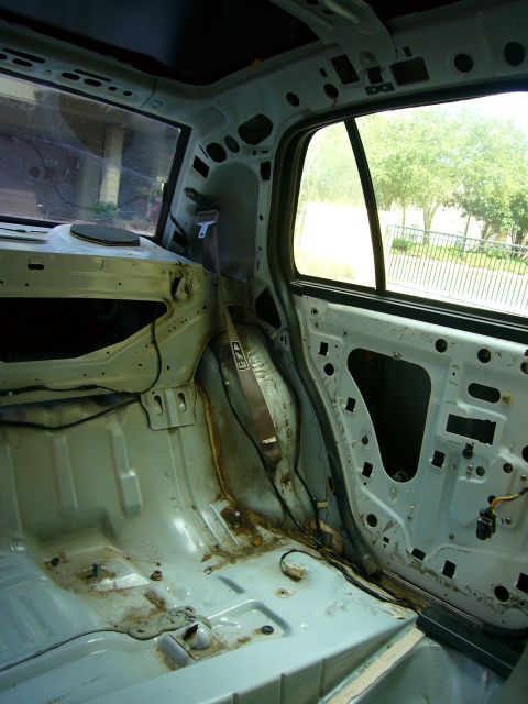 2001 Ford Crown Victoria - The interior of a car has been stripped down, revealing the bare metal frame and wiring beneath the panels.