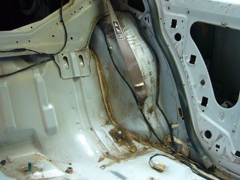 2001 Ford Crown Victoria - Close-up of a car's interior structural components, showing signs of rust and dirt.