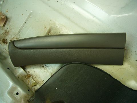 2001 Ford Crown Victoria - A dark gray interior trim piece is visible on the floor of a vehicle, surrounded by dirt and debris.