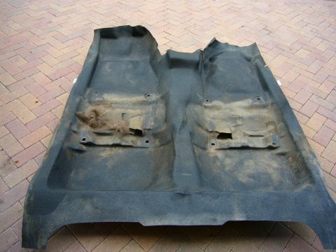 2001 Ford Crown Victoria - A removed and dirty car floor mat lies on a brick patio, showing signs of wear and tear.