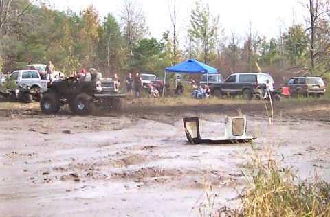 1978 Ford Bronco - Muddy field with several off-road vehicles and spectators enjoying an event.