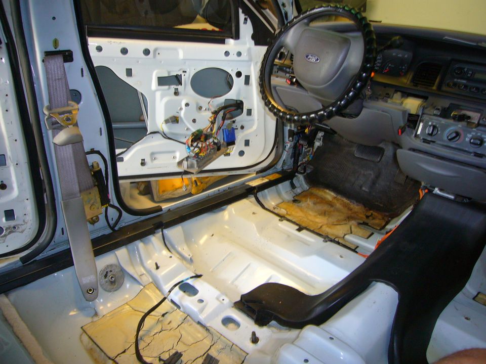 2001 Ford Crown Victoria interior stripped down, showing door panel removed, wiring, and bare floor