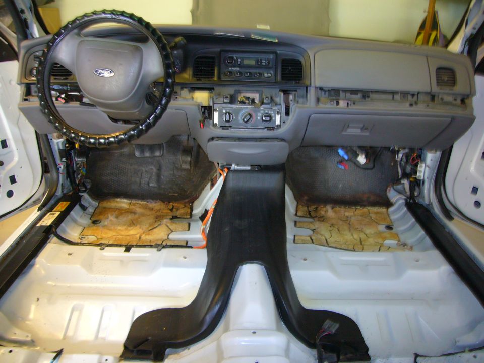 Interior of a 2001 Ford Crown Victoria with dashboard and seats removed, showing exposed floor and wiring