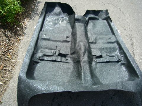 2001 Ford Crown Victoria - Car floor carpet removed and placed on asphalt, showing its molded shape and mounting points.