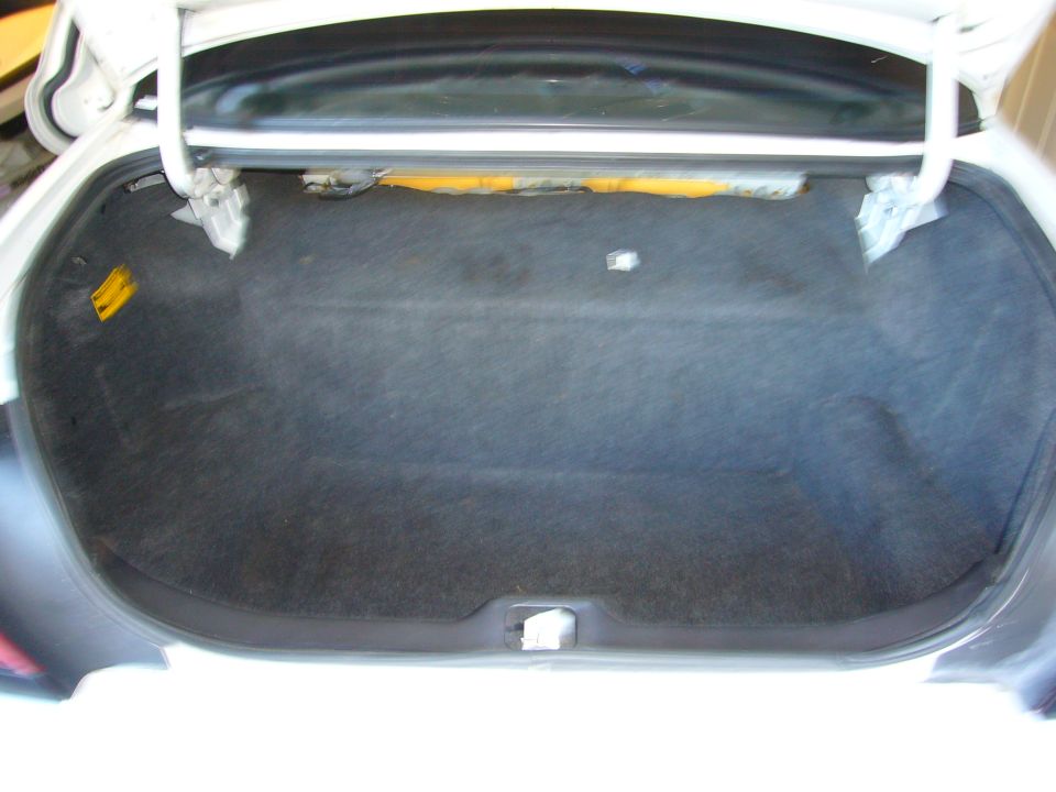 open car trunk with dark carpet lining and yellow insulation visible