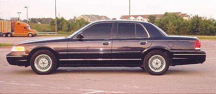 Side view of a dark blue Ford Crown Victoria sedan parked on asphalt