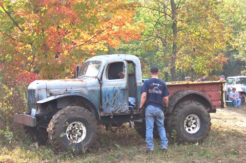 1978 Ford Bronco - A man stands beside a heavily modified, older truck with large tires, parked outdoors with autumn foliage.