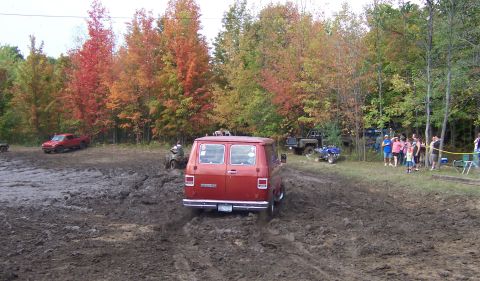 1978 Ford Bronco - A red van navigates a muddy track surrounded by trees displaying autumn colors.