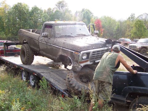 1978 Ford Bronco - Muddy 1977 Ford F-Series pickup truck loaded onto a trailer, with "BARNYARD DOGS" on the windshield.