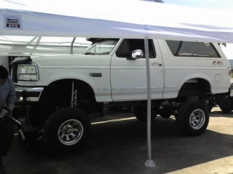 1995 Ford Bronco - This lifted 1995 Ford Bronco is parked under a canopy, showing its side profile.