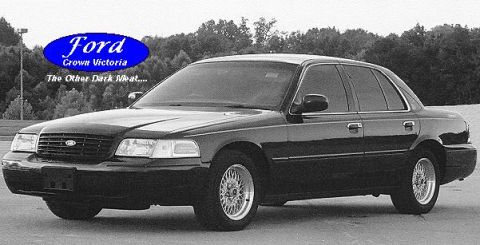 1999 Ford Crown Victoria - Black Ford Crown Victoria sedan with aftermarket wheels, seen from the front quarter.