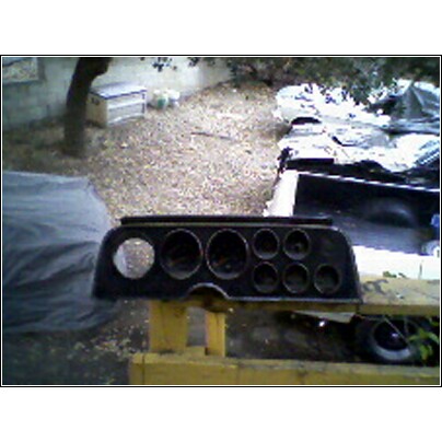 1973 Ford Ranchero - A dashboard instrument cluster, possibly from a 1973 Ford Ranchero, sits on a yellow stand outdoors.