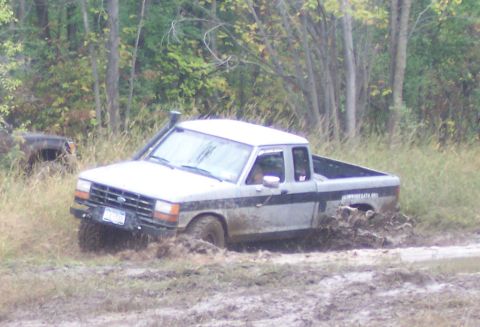 1978 Ford Bronco - A silver Ford Ranger pickup truck is stuck in the mud, with its tires deep in the mire.