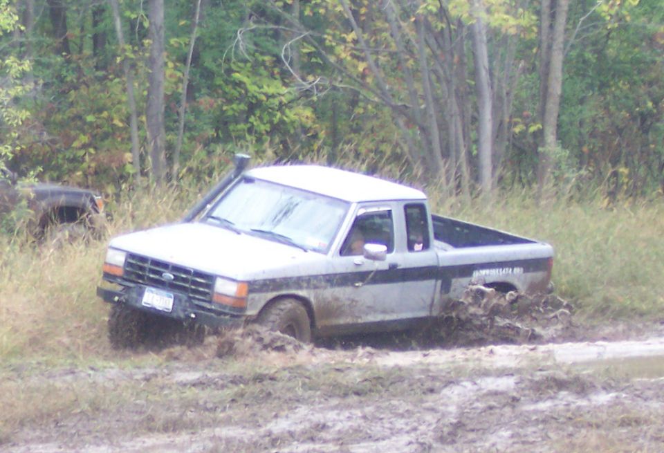 Silver Ford Ranger pickup truck stuck in mud, with snorkel and off-road tires
