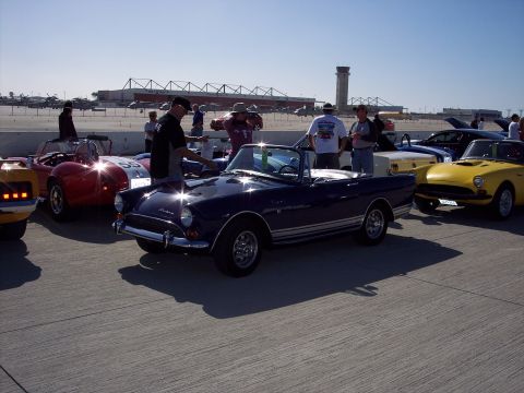 1971 Ford Mustang - Several classic cars are gathered outdoors on a sunny day, with a dark blue convertible in the foreground.