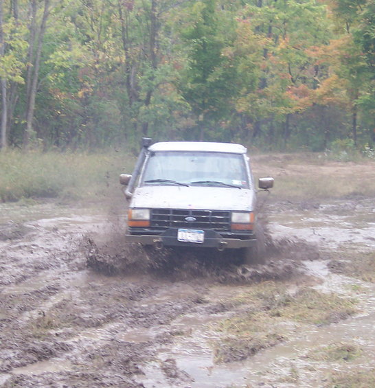 White 1990 Ford Ranger driving through mud, splashing water, with snorkel
