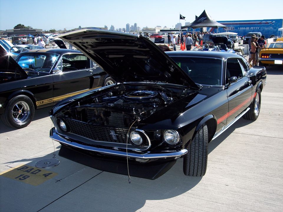Black 1969 Ford Mustang Mach 1 with hood open, parked next to another Mustang