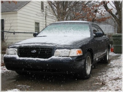1999 Ford Crown Victoria - A black 1999 Ford Crown Victoria is parked outside in the snow, with snow covering its hood and windshield.