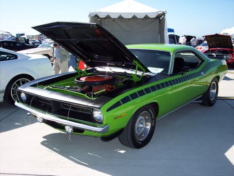 1971 Ford Mustang - A bright green 1970 Plymouth Barracuda is displayed with its hood open at an outdoor car show.