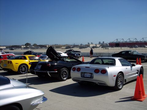 1971 Ford Mustang - A collection of sports cars are parked outdoors under a clear blue sky with a city skyline in the distance.