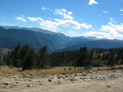 1995 Ford Bronco - A scenic view of mountains and pine trees under a bright blue sky with scattered clouds.