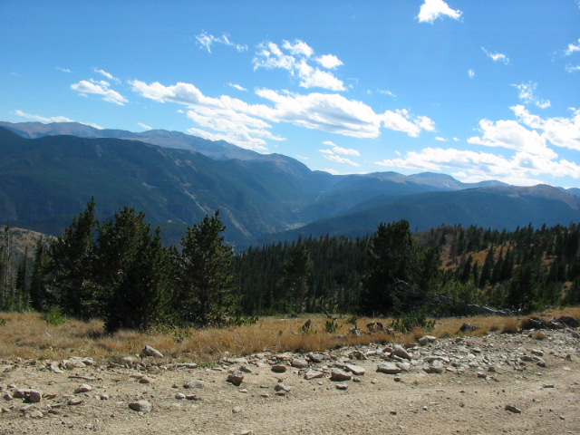 Mountain valley overlook with pines and distant ridges, no vehicle in frame