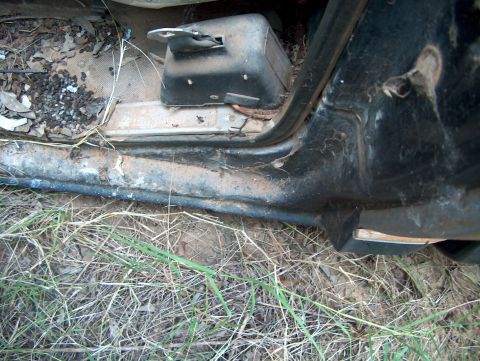 1979 Ford Bronco - Close-up of a vehicle's interior door sill and floor area, showing debris and grass.