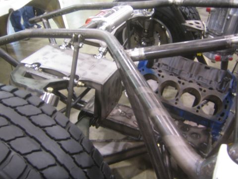 1990 Ford Bronco - close-up of an off-road tube-frame chassis shows a bare engine block, exhaust tubing and rear suspension components.