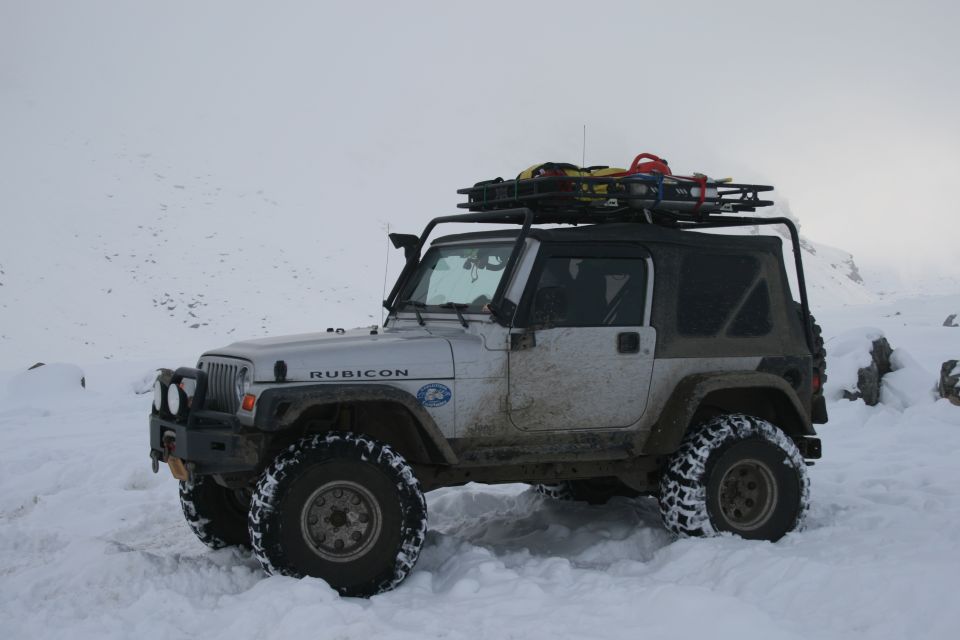Silver 2003 Jeep TJ Rubicon with roof rack in snow. "RUBICON" text visible on fender