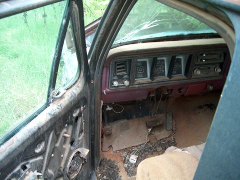 1979 Ford Bronco - Interior view of a 1979 Ford Bronco, showing its worn dashboard and missing door panel.