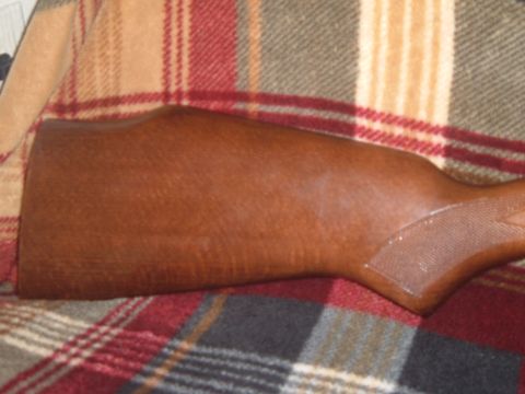 1919 Yugo Vega - Close-up of a wooden rifle stock resting on a plaid blanket.
