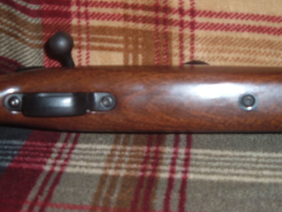 Bolt-action rifle stock and receiver on plaid blanket