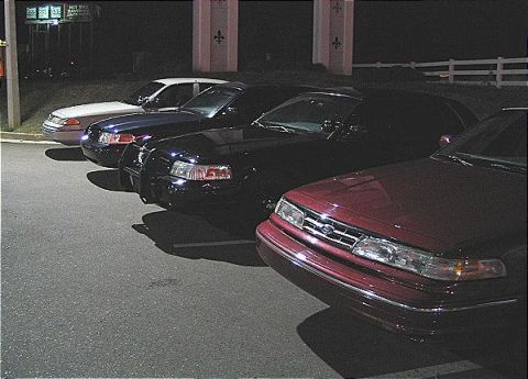 1999 Ford Crown Victoria - Multiple Ford Crown Victorias are parked in a row at night, their front ends.