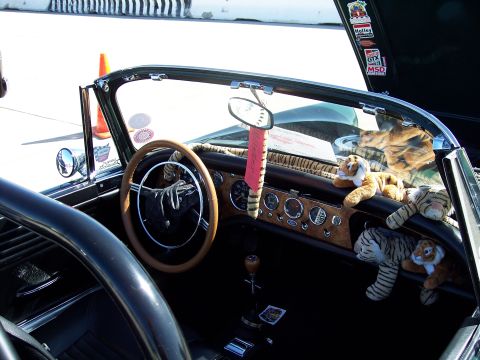 1971 Ford Mustang - The interior of a convertible is shown, a wood-grain dashboard, multiple gauges, and several stuffed tiger toys.