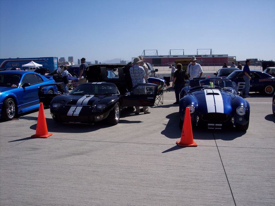Black Ford GT with white stripes parked next to a blue Shelby Cobra with white stripes