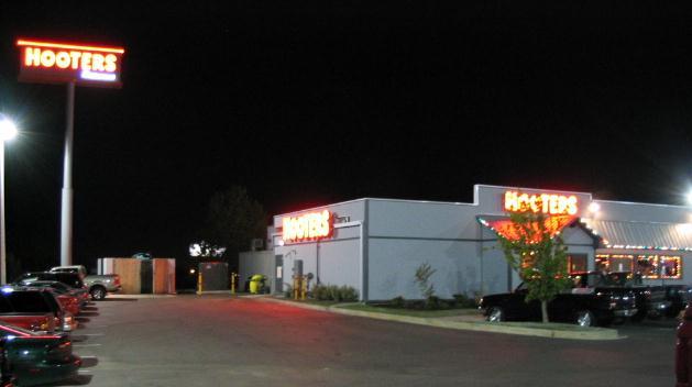 Cars parked at night in front of a Hooters restaurant