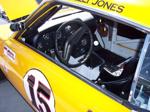 1971 Ford Mustang - Interior view of a yellow 1971 Ford Mustang race car, showing the dashboard, steering wheel, and driver's seat.