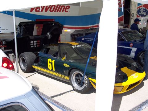 1971 Ford Mustang - A Ford GT race car with sponsor decals is parked under a tent next to another vehicle.