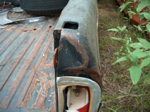 1979 Ford Bronco - The rear corner of a vehicle shows significant rust and damage, with a partially visible taillight assembly.