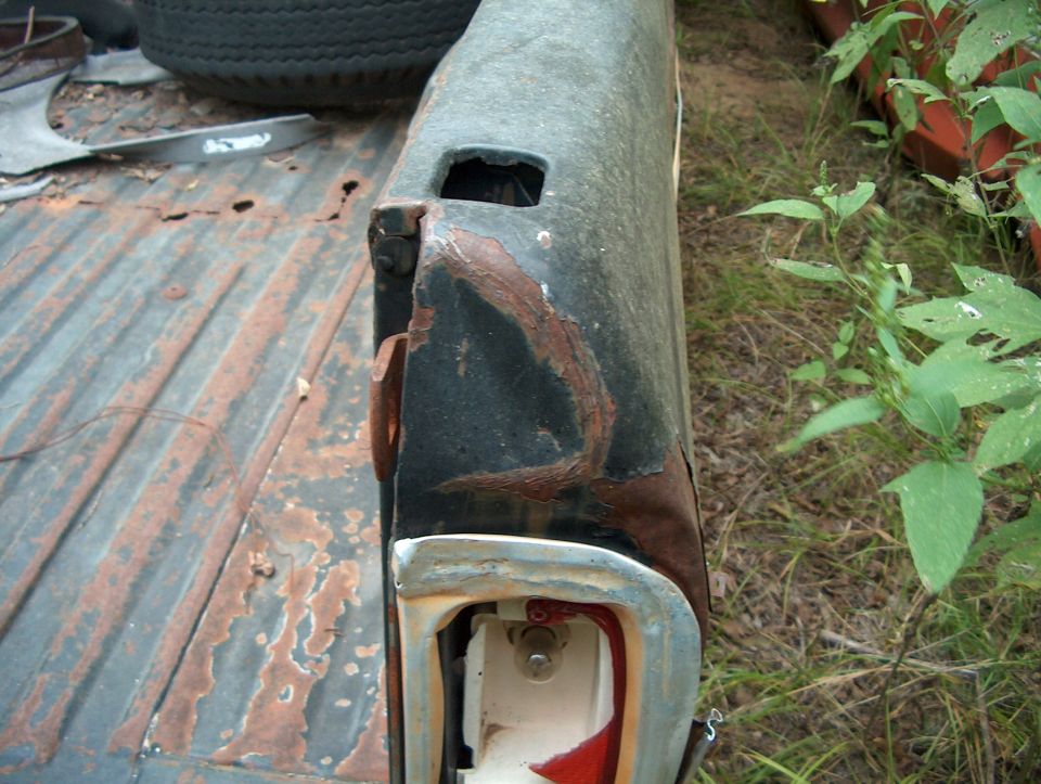 close-up of a rusty truck bed corner, showing a taillight housing and corrugated metal