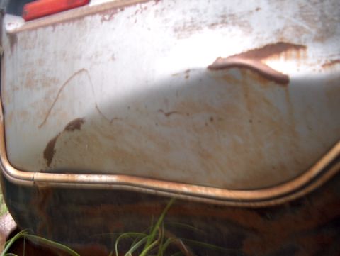 1979 Ford Bronco - Close-up of a weathered white rear quarter panel, showing rust and dirt accumulation.
