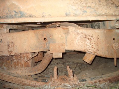 1979 Ford Bronco - Undercarriage view of heavily rusted vehicle frame and suspension components.