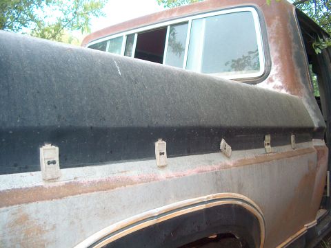 1979 Ford Bronco - The weathered side of a pickup truck bed shows signs of age and disuse, with rust visible on the body panels.