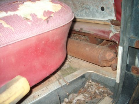 1979 Ford Bronco - The interior of a dilapidated vehicle shows a worn seat and a rusty driveshaft.