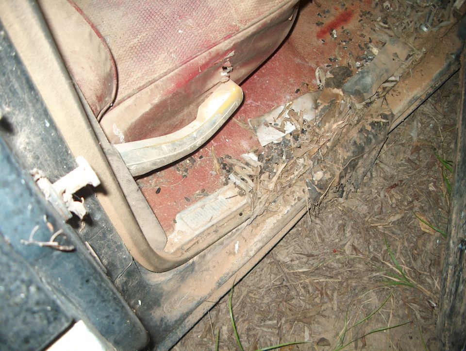 Car interior door sill with red upholstery and debris