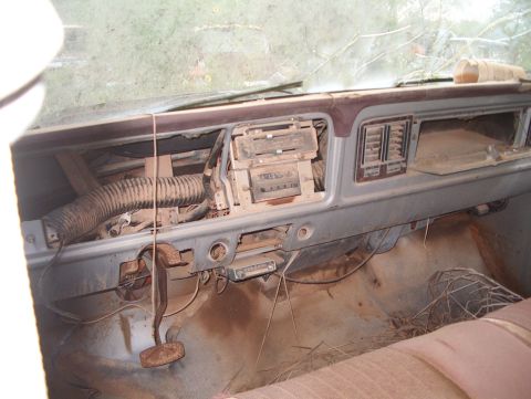 1979 Ford Bronco - Interior view of a 1979 Ford Bronco, showing the dashboard and floor covered in dust and debris.